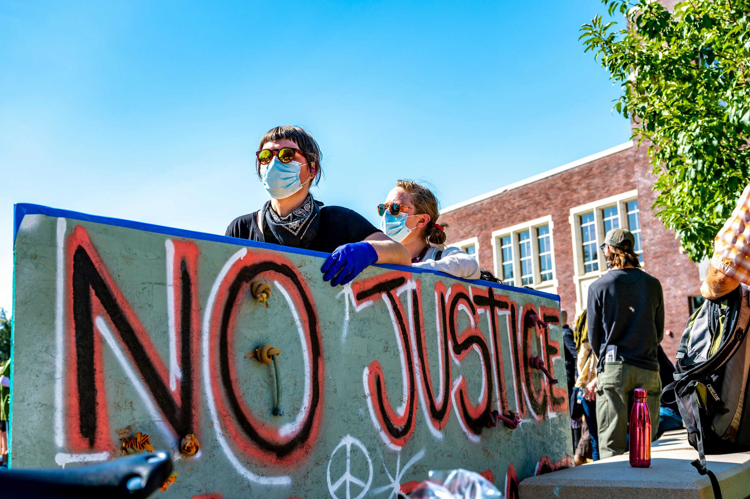 protestors hold a cardboard sign that says "no justice"